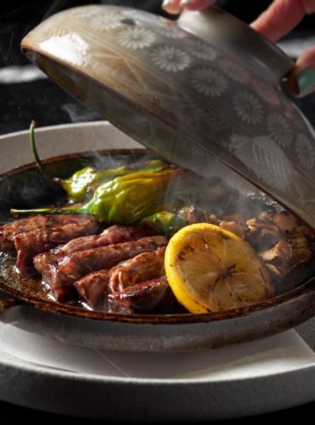 Food on a hot plate while person is pulling the cover off