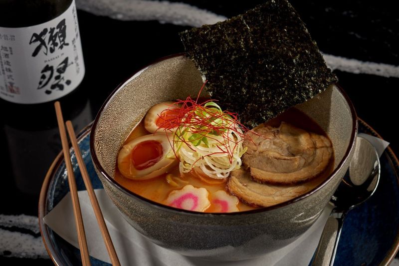 Soup in a round tan bowl with chopsticks