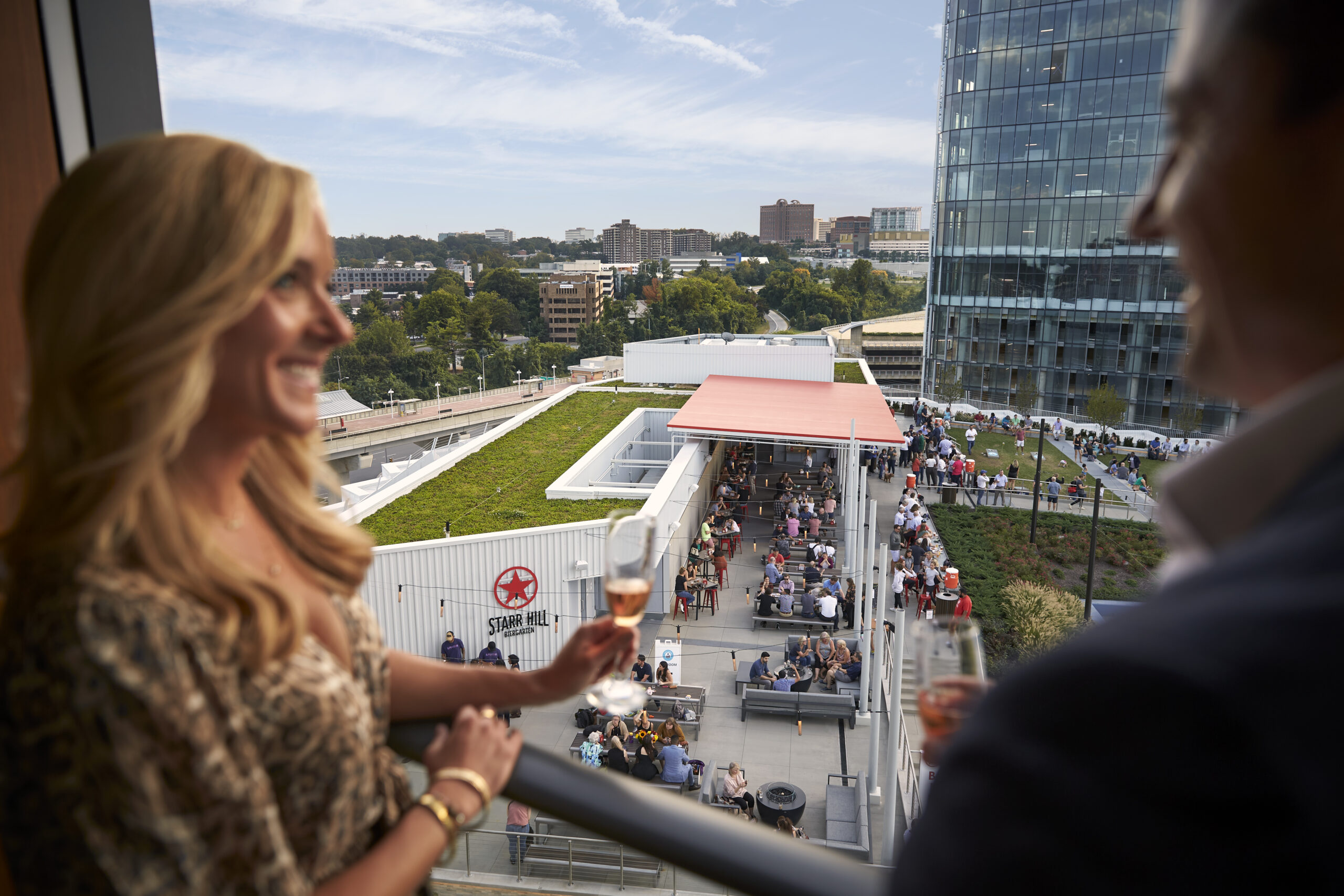 Couple enjoying drinks on balcony with event view.