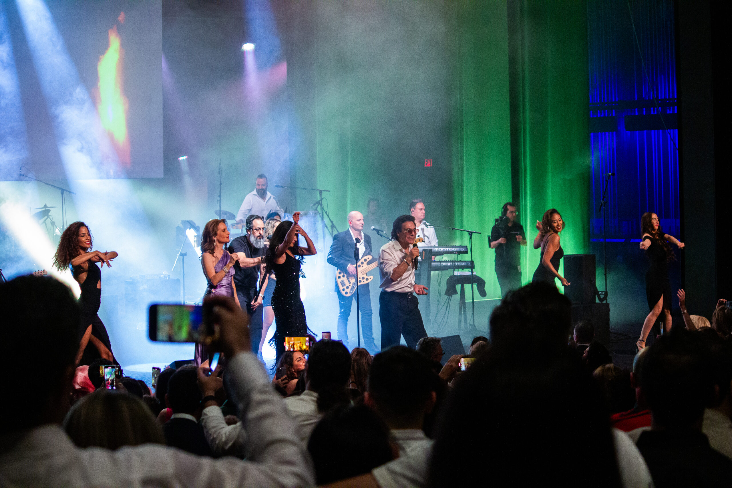 People recording and enjying live performance on stage.