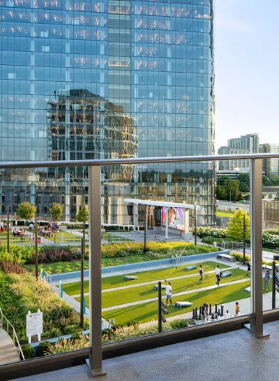 City view from a corner balcony with glass railing and a table.